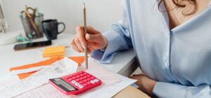 Kobieta z kalkulatorem i dokumentami przy biurku analizująca finanse - rozdzielność majątkowa czy wspólność